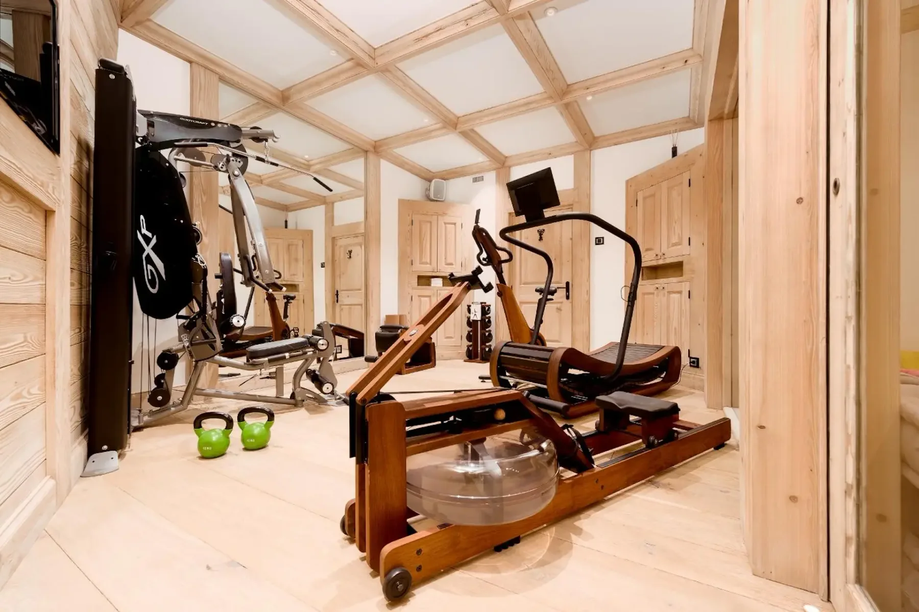 Un gimnasio con máquinas de ejercicio y pesas en una sala revestida de madera.