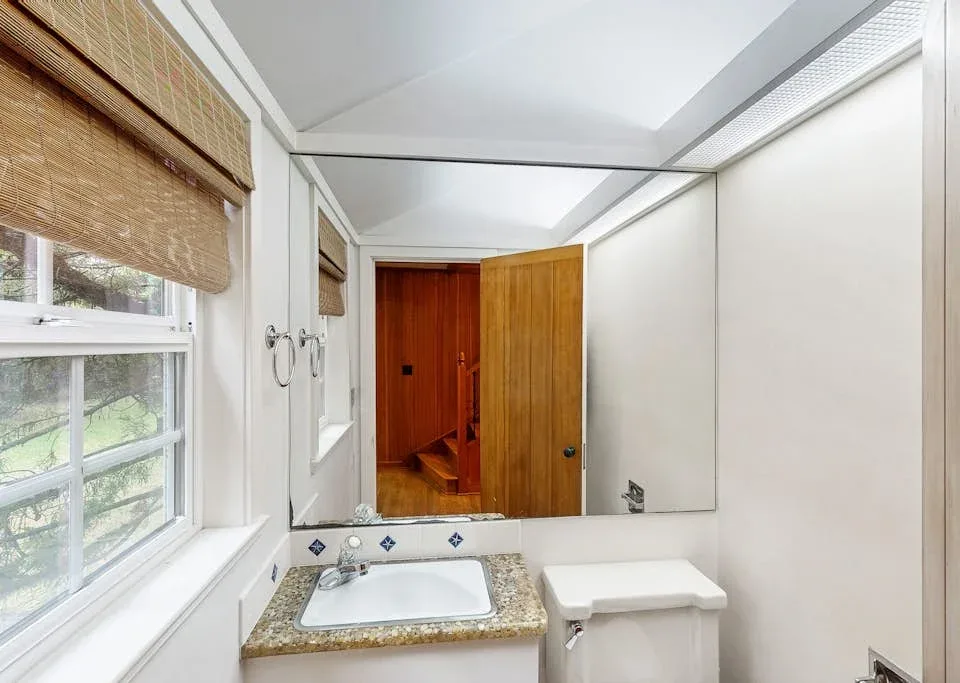 A bright bathroom with a sink beneath a large wall mirror.