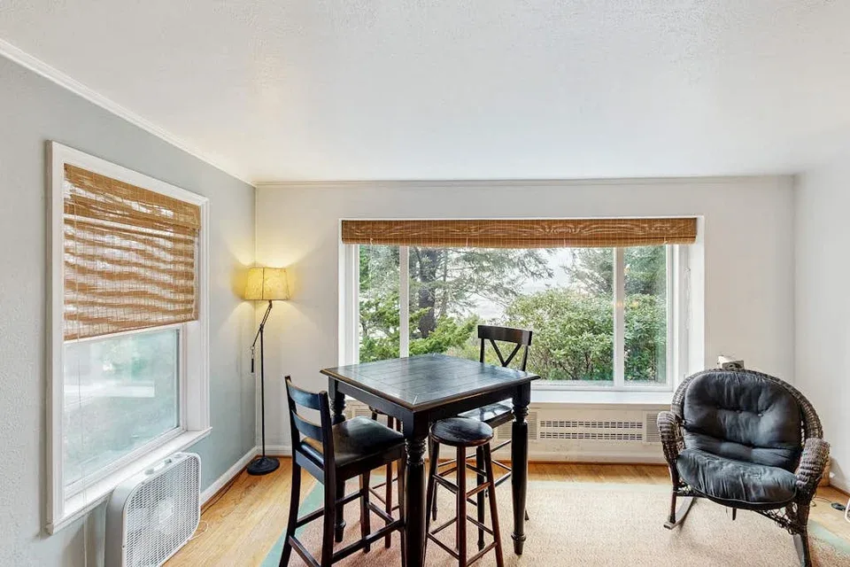 A dining area with a table and seating beside large windows.