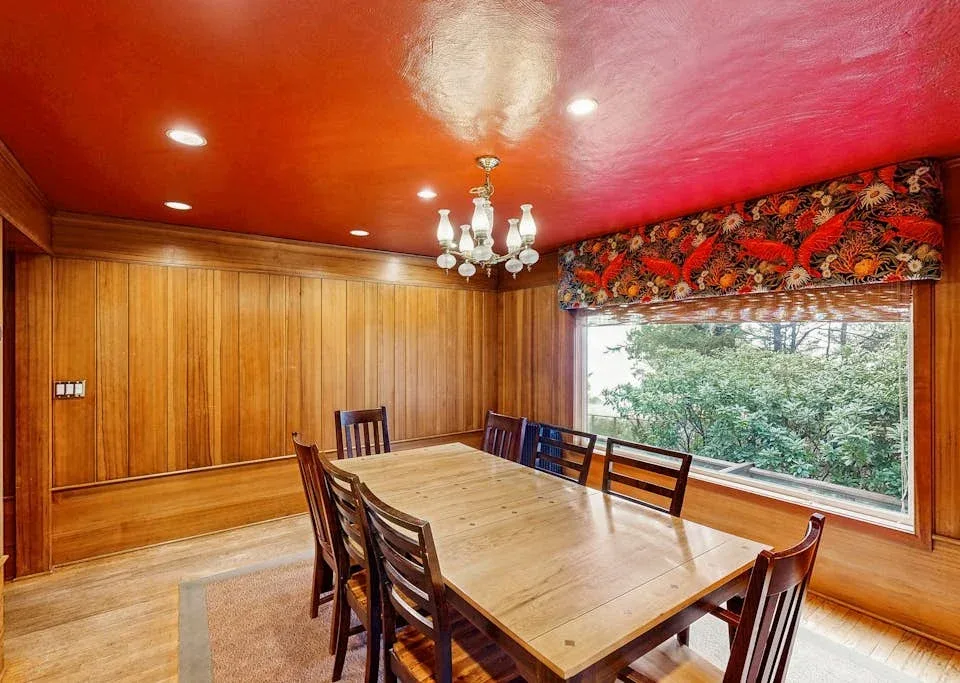 A wood-paneled dining room with a large table beside a wide window.