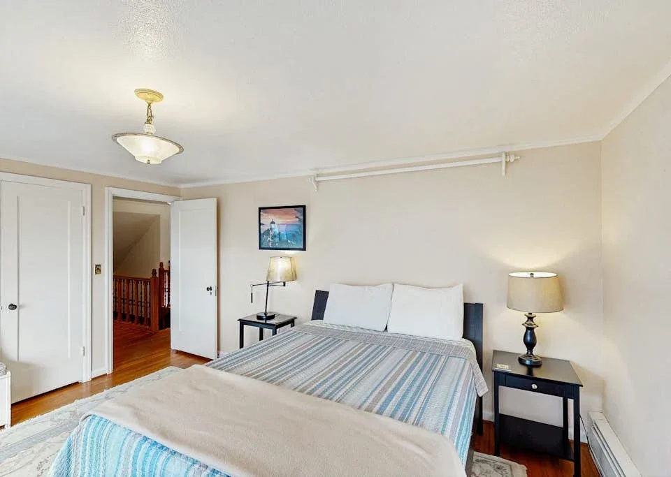 A bedroom with a bed, bedside tables, and an open doorway.