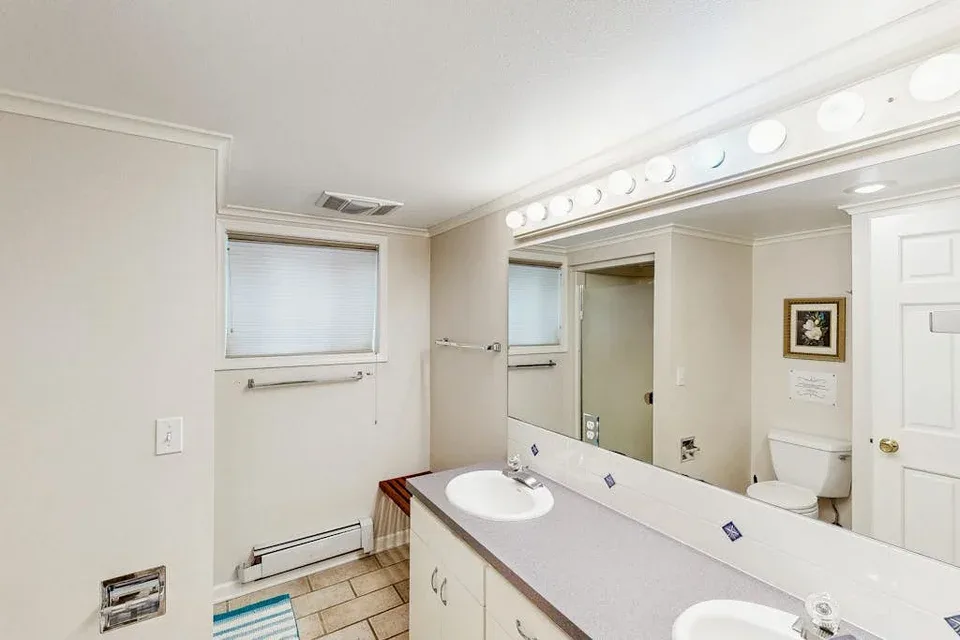 A bright bathroom with a long vanity, mirrors, and a bathtub.