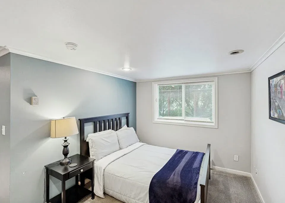 A bedroom with a bed, bedside table, and window.
