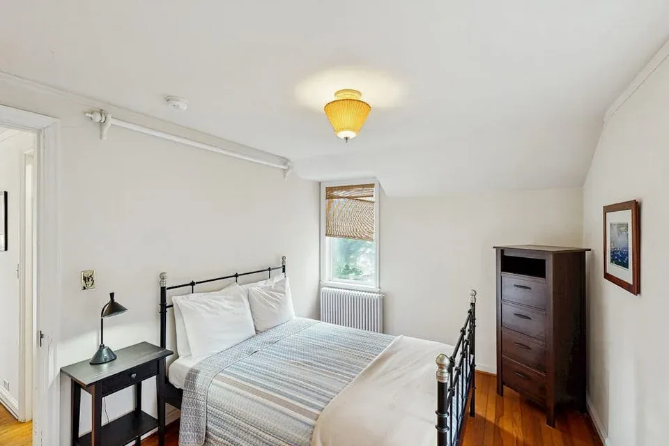 A bedroom with a bed, a bedside table, and a chest of drawers.