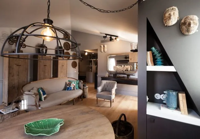 Una sala de estar con sofá, sillón y estanterías decorativas.