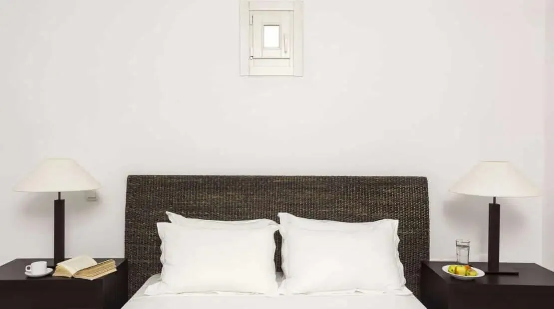 Bedroom with a bed, white pillows, and matching bedside lamps.