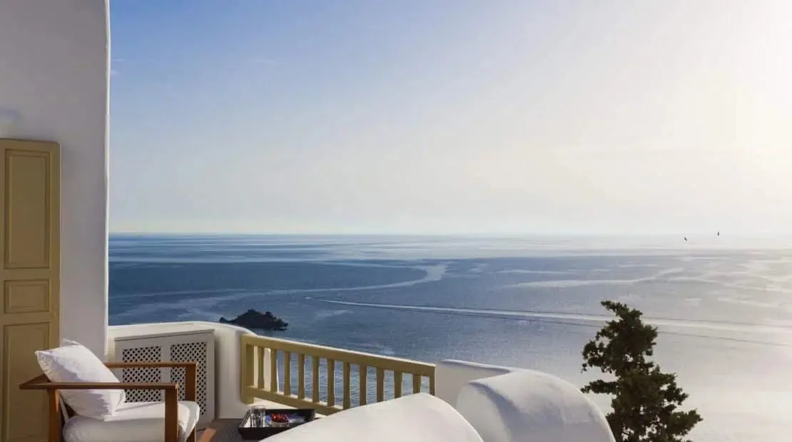 A seaside balcony with seating overlooks the ocean.
