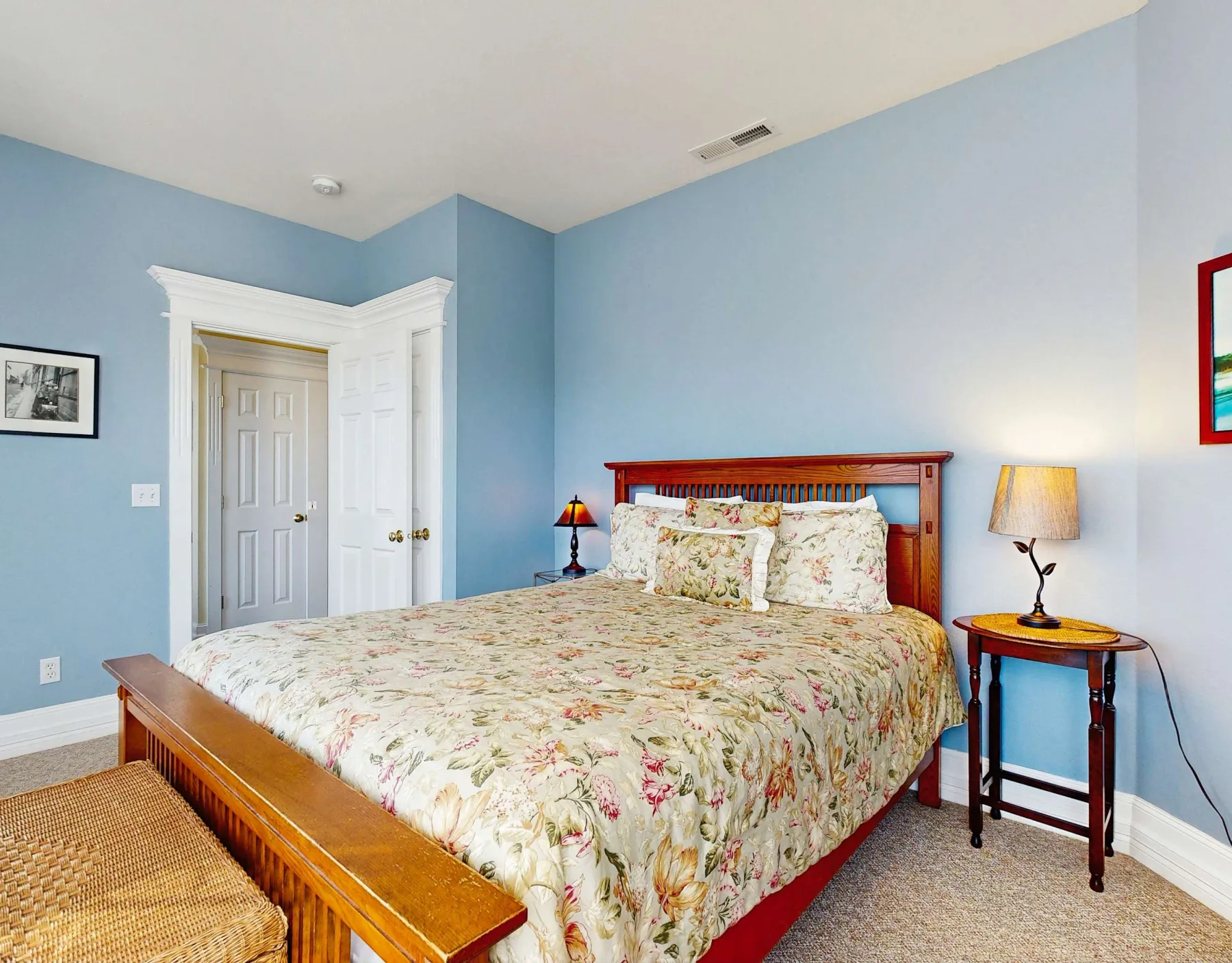 Un dormitorio con una cama de madera cubierta con ropa de cama floral y paredes azules.