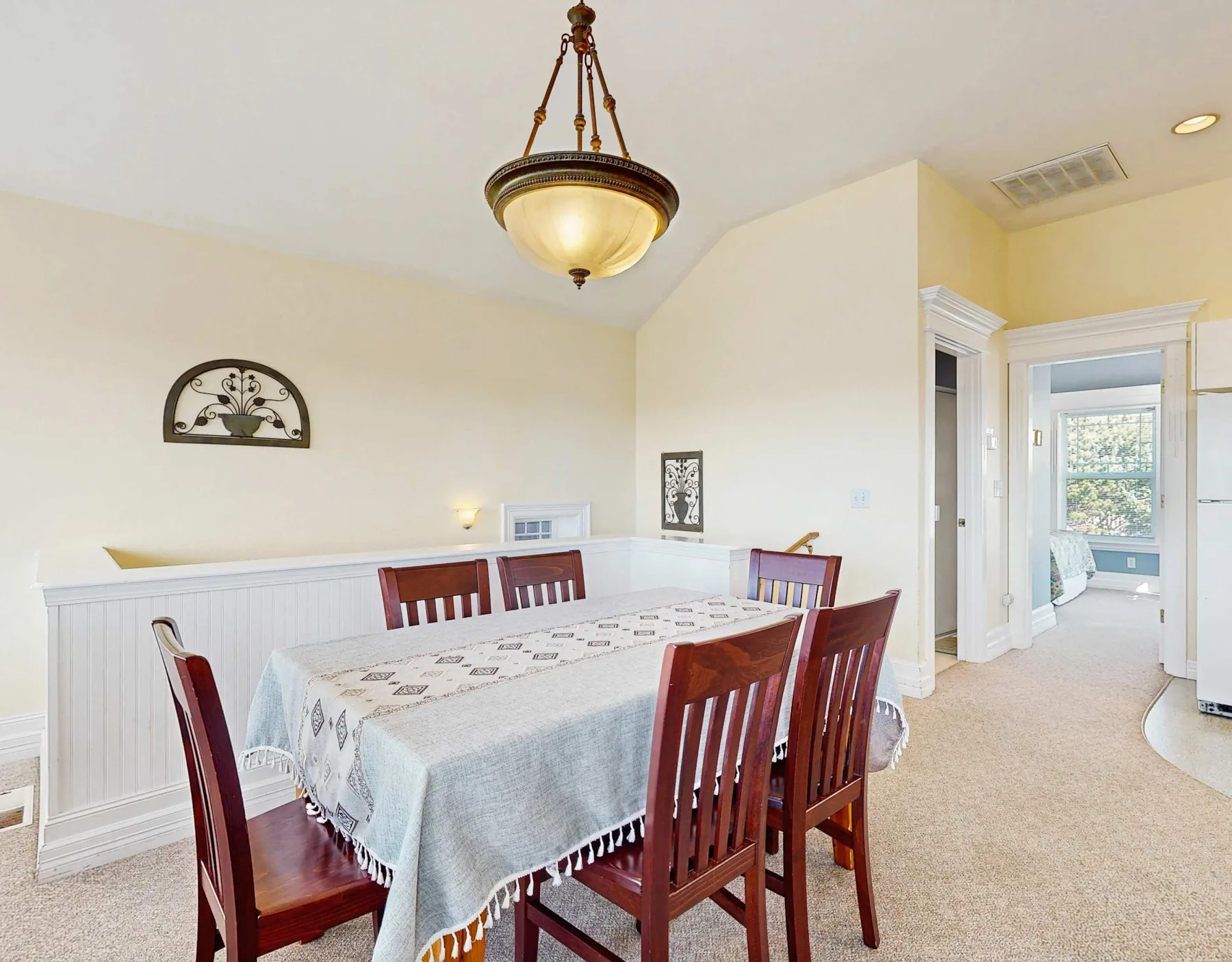 Comedor con una mesa rectangular, asientos de madera y una lámpara colgante.