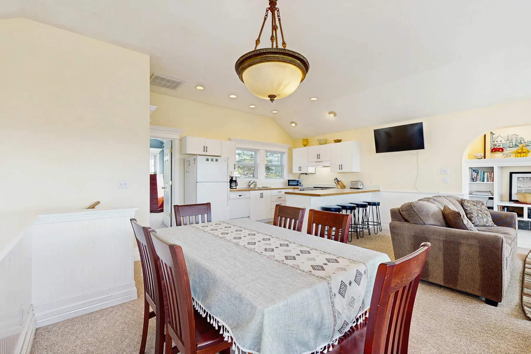 Un espacio abierto de comedor y sala incluye una mesa, asientos y una cocina.