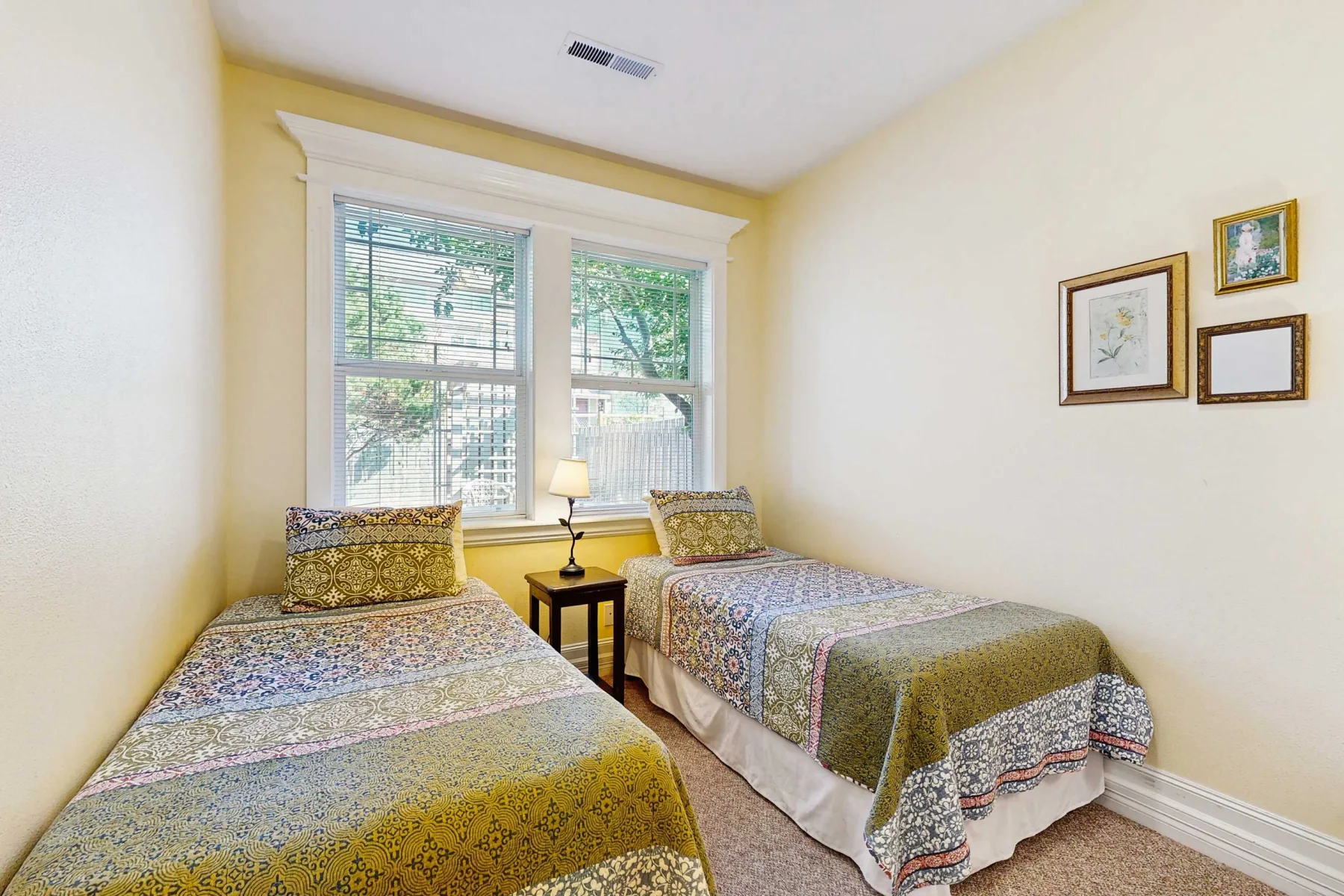 Un dormitorio con dos camas, ropa de cama estampada y una ventana.