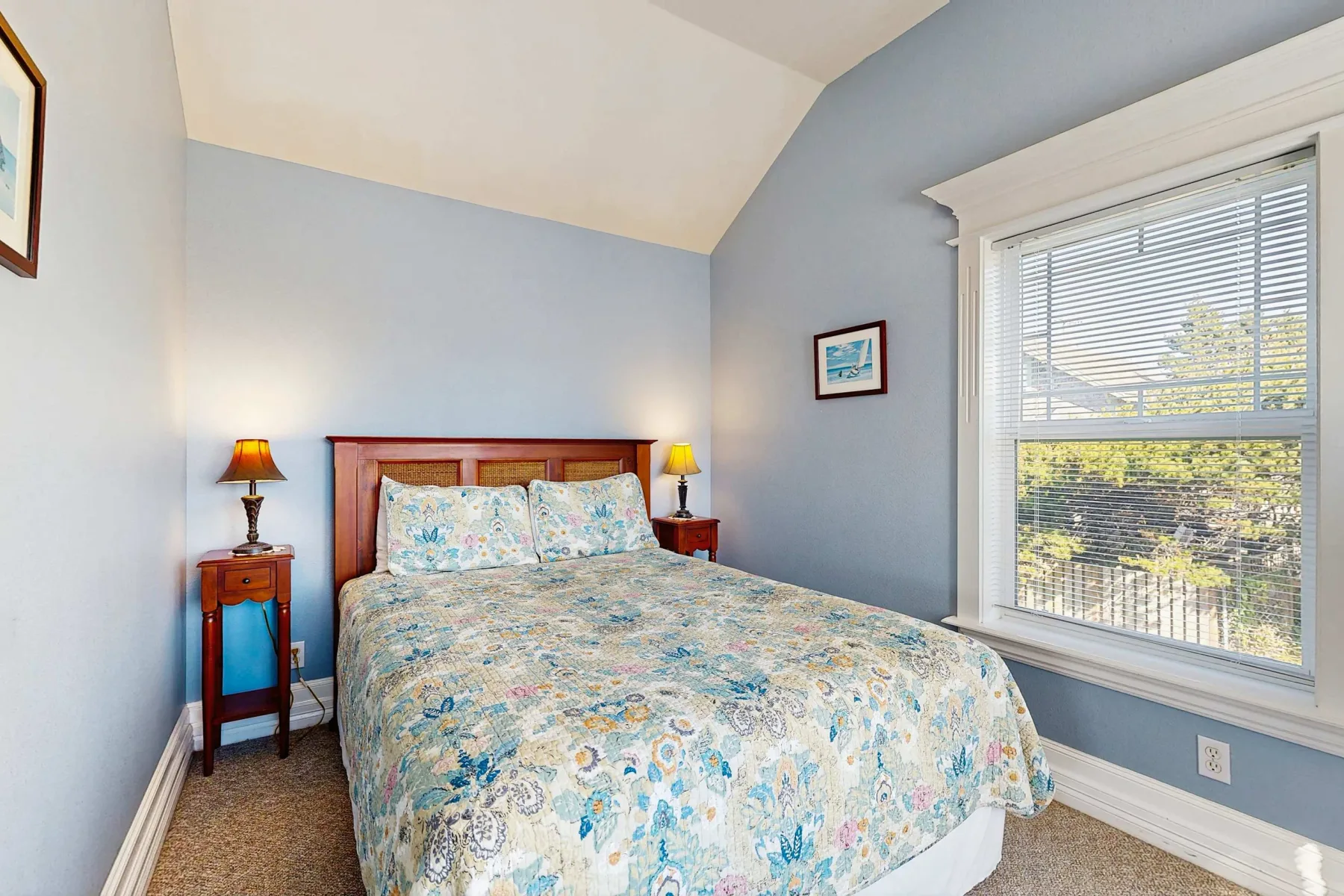 Un dormitorio con una cama cubierta con una colcha floral junto a una ventana grande.