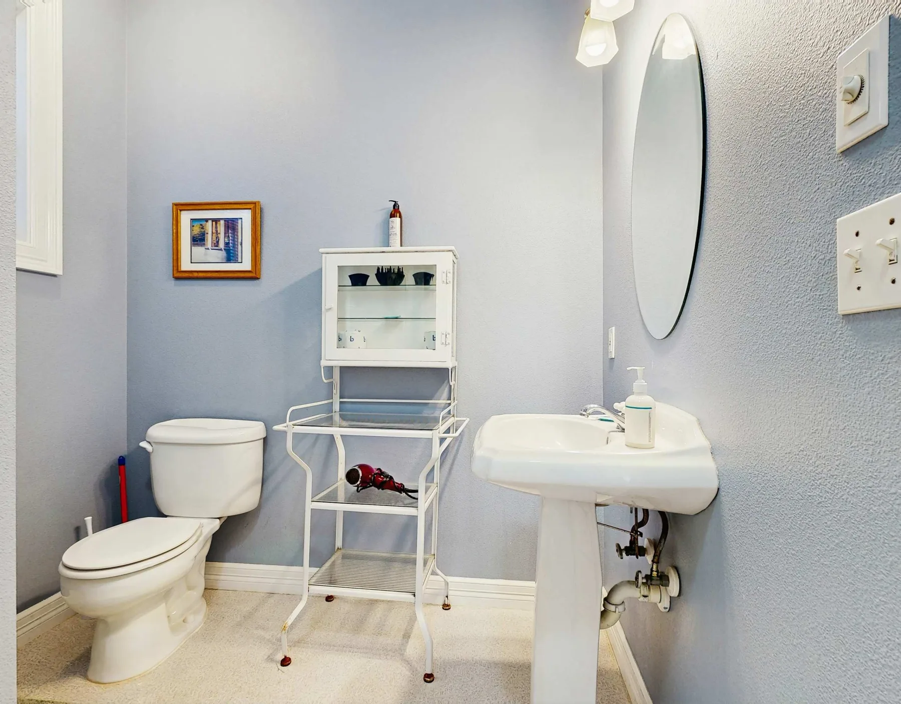 Un baño con inodoro, lavabo y un pequeño armario.