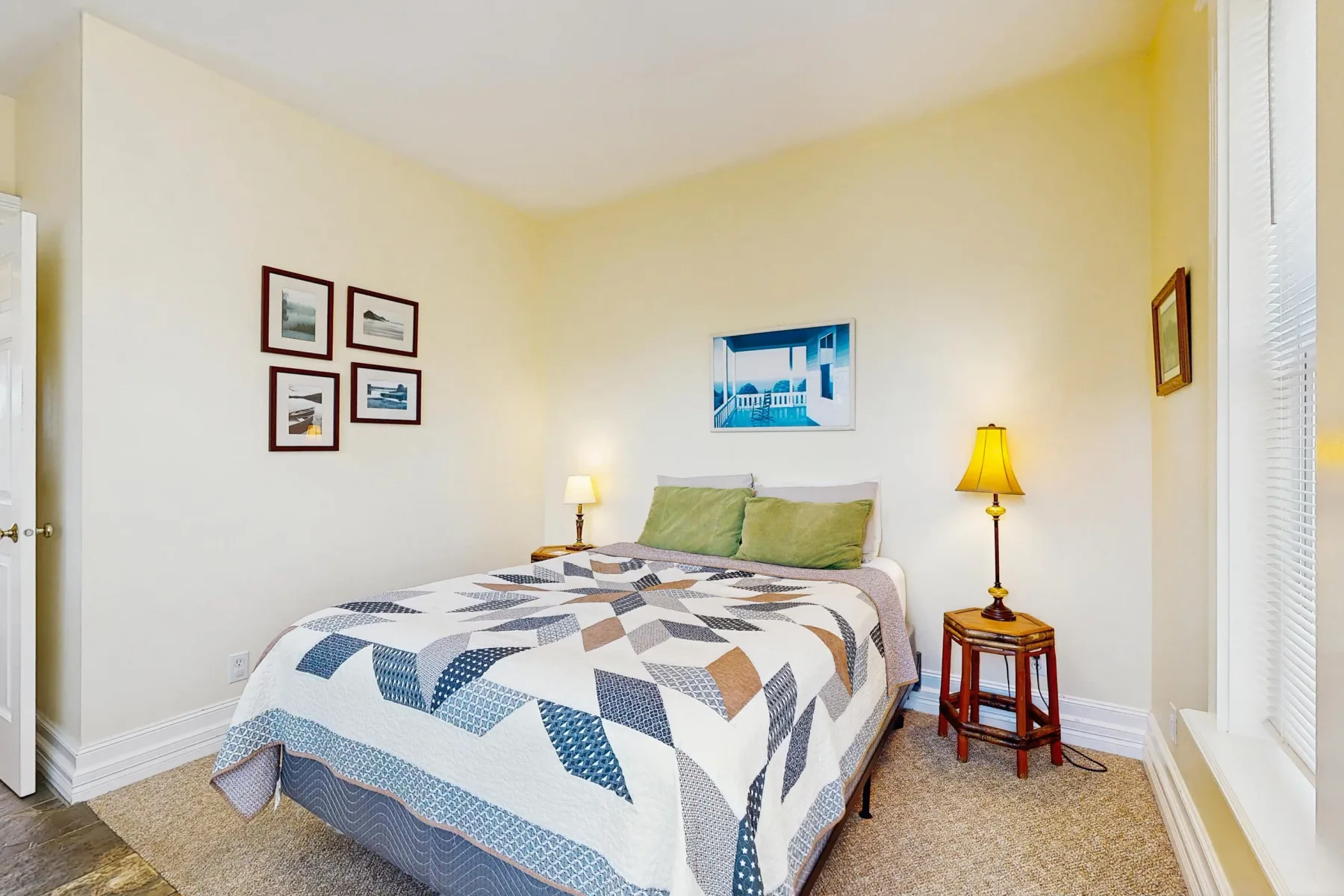 Un dormitorio con una cama cubierta con una colcha geométrica azul y blanca.