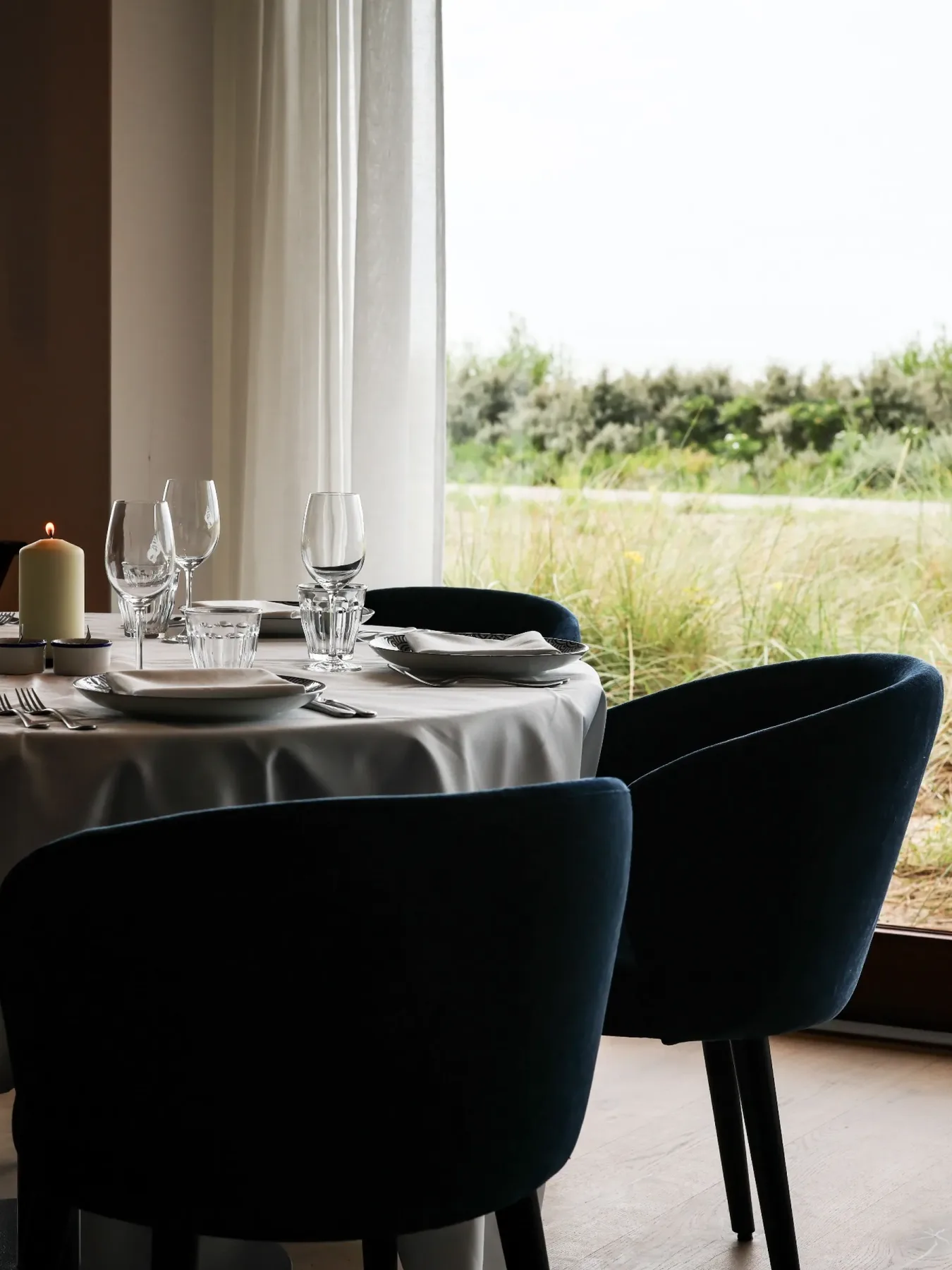 Representative hotel space: A dining table is set beside a large window overlooking a grassy landscape.
