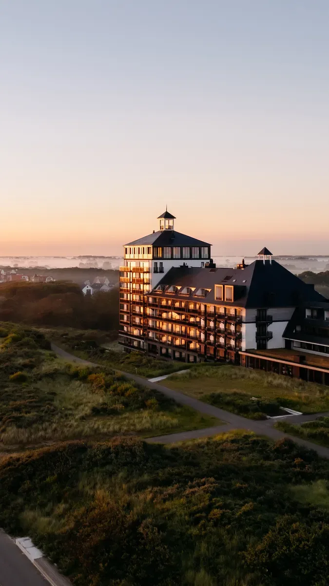 Representative hotel space: A large hotel building stands beside landscaped grounds at sunset.