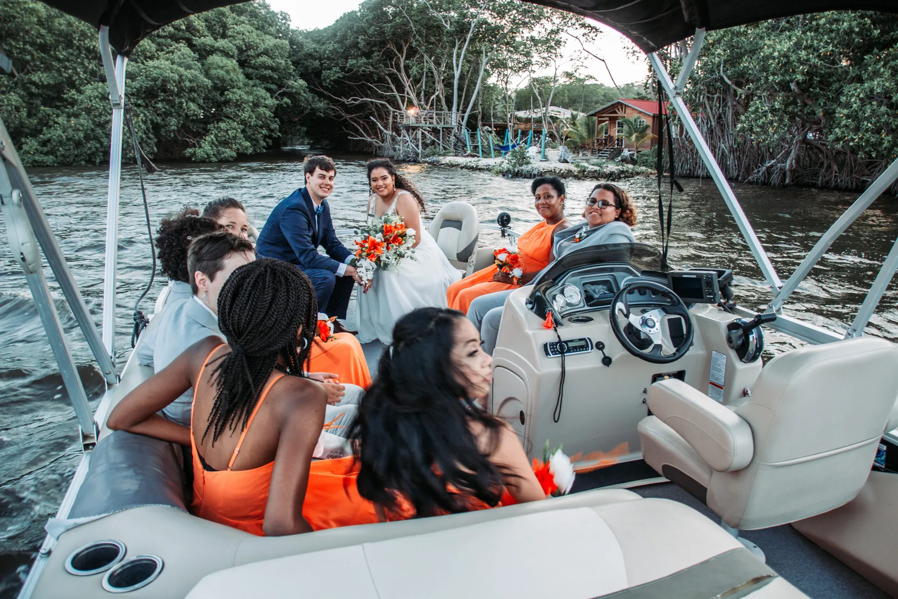 Representative hotel space: People ride in a covered motorboat on a tree-lined river.