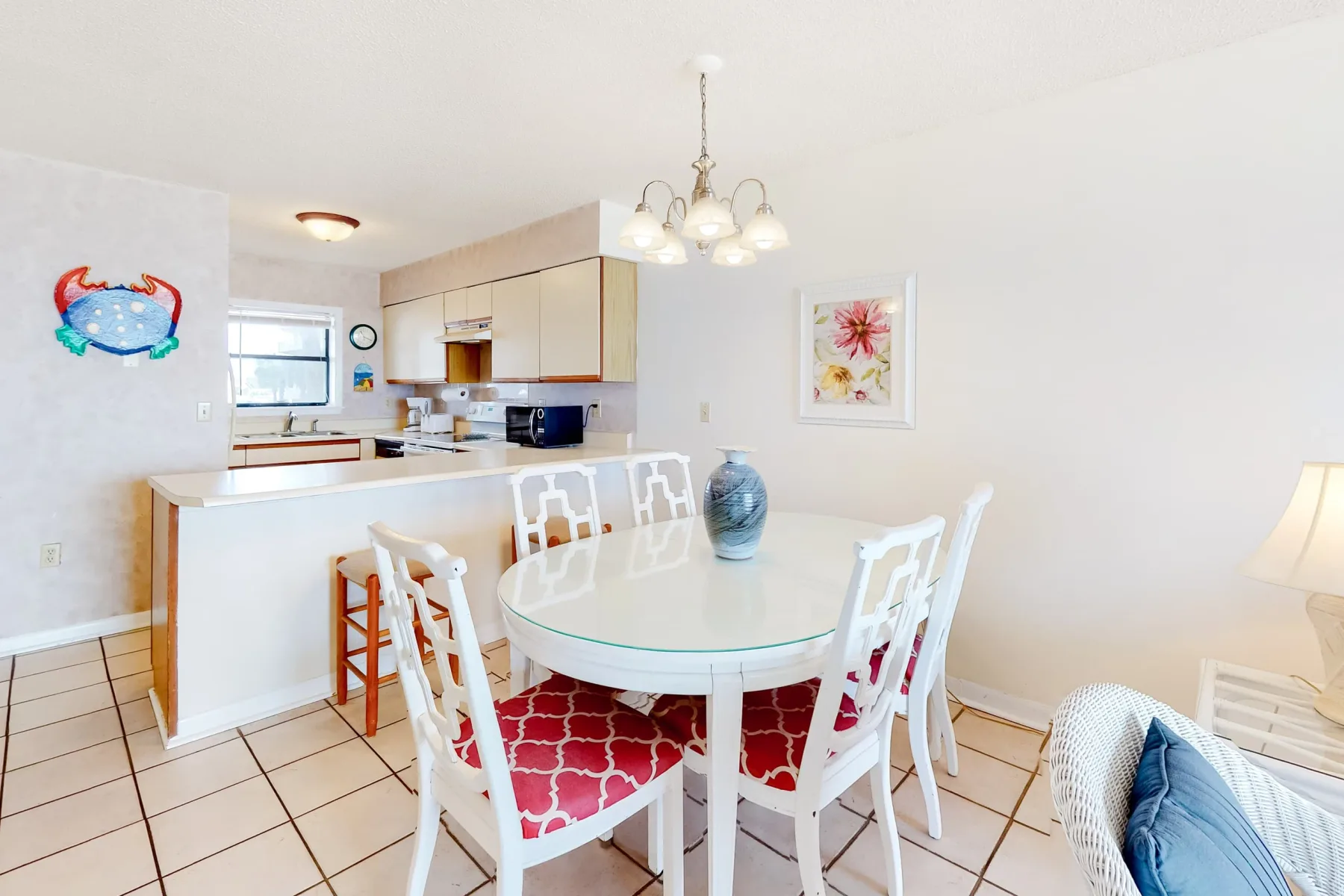 Un comedor luminoso con una mesa blanca y una cocina abierta al fondo.
