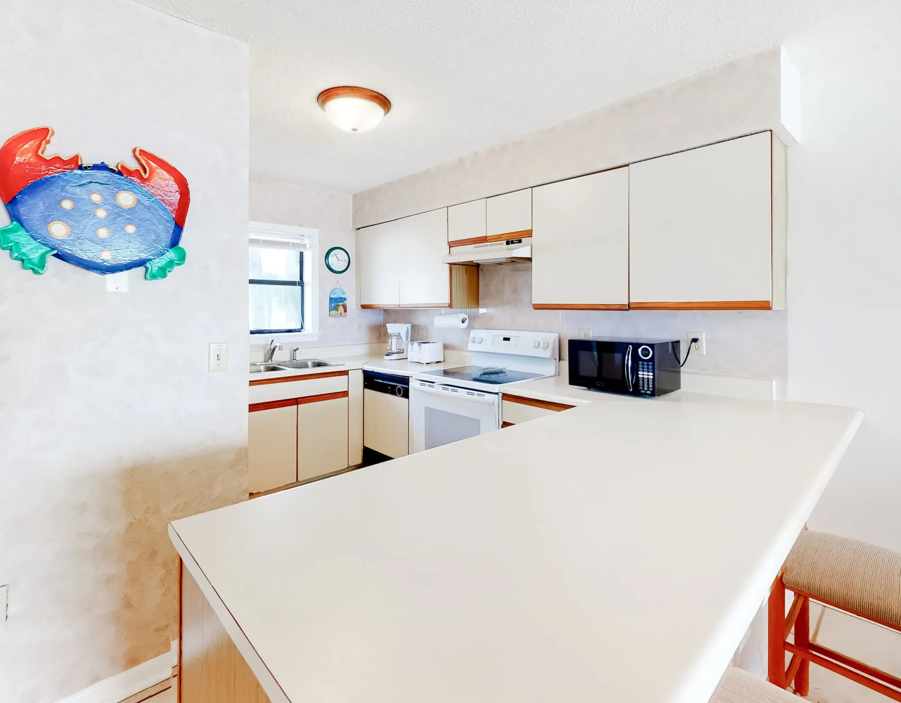 Una cocina luminosa con gabinetes blancos, una estufa y una amplia encimera.