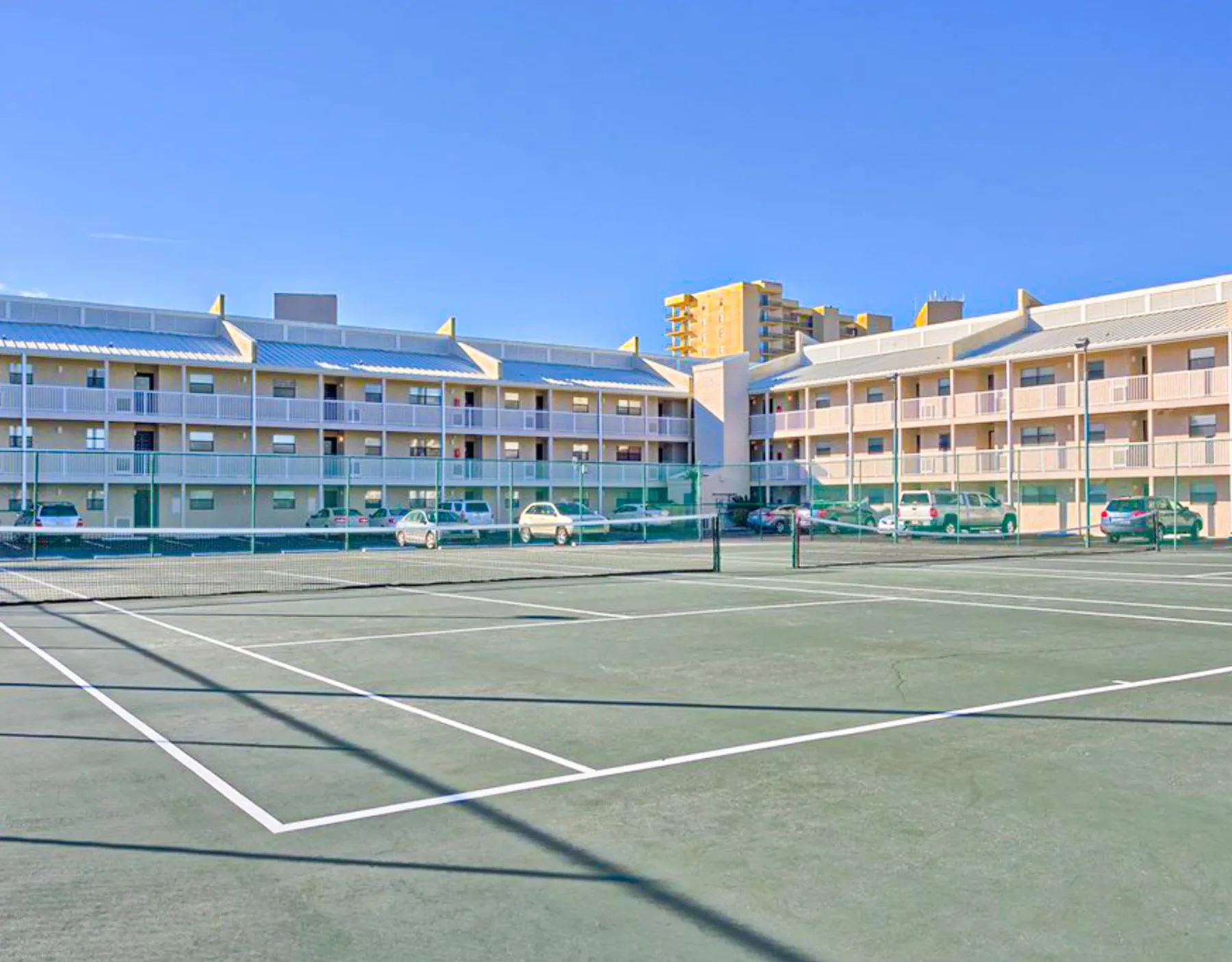 Zona común: Una cancha al aire libre con líneas blancas y edificios al fondo.