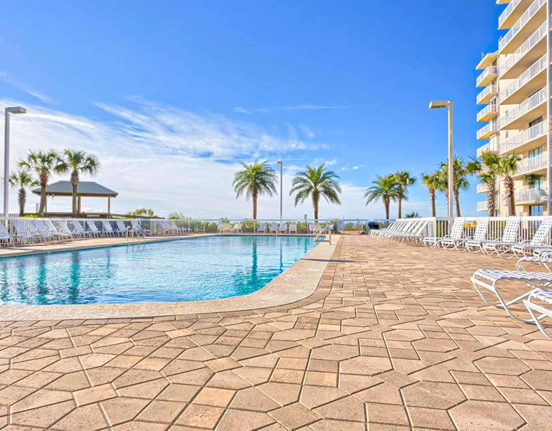 Zona común: Piscina al aire libre rodeada de una terraza pavimentada y asientos.