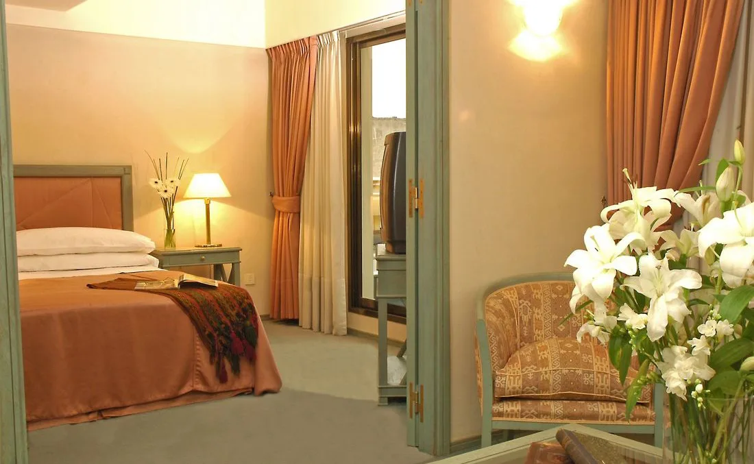 Representative hotel space: A bedroom with a neatly made bed and curtains beside a glass doorway.