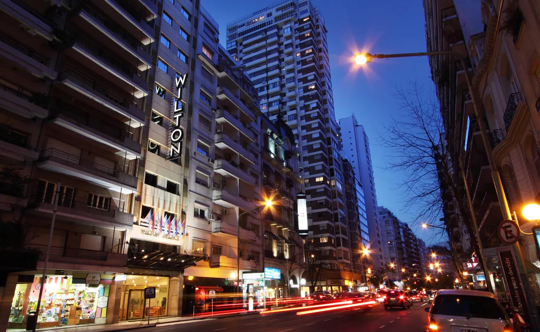 Representative hotel space: A city street at dusk with illuminated buildings and passing traffic.