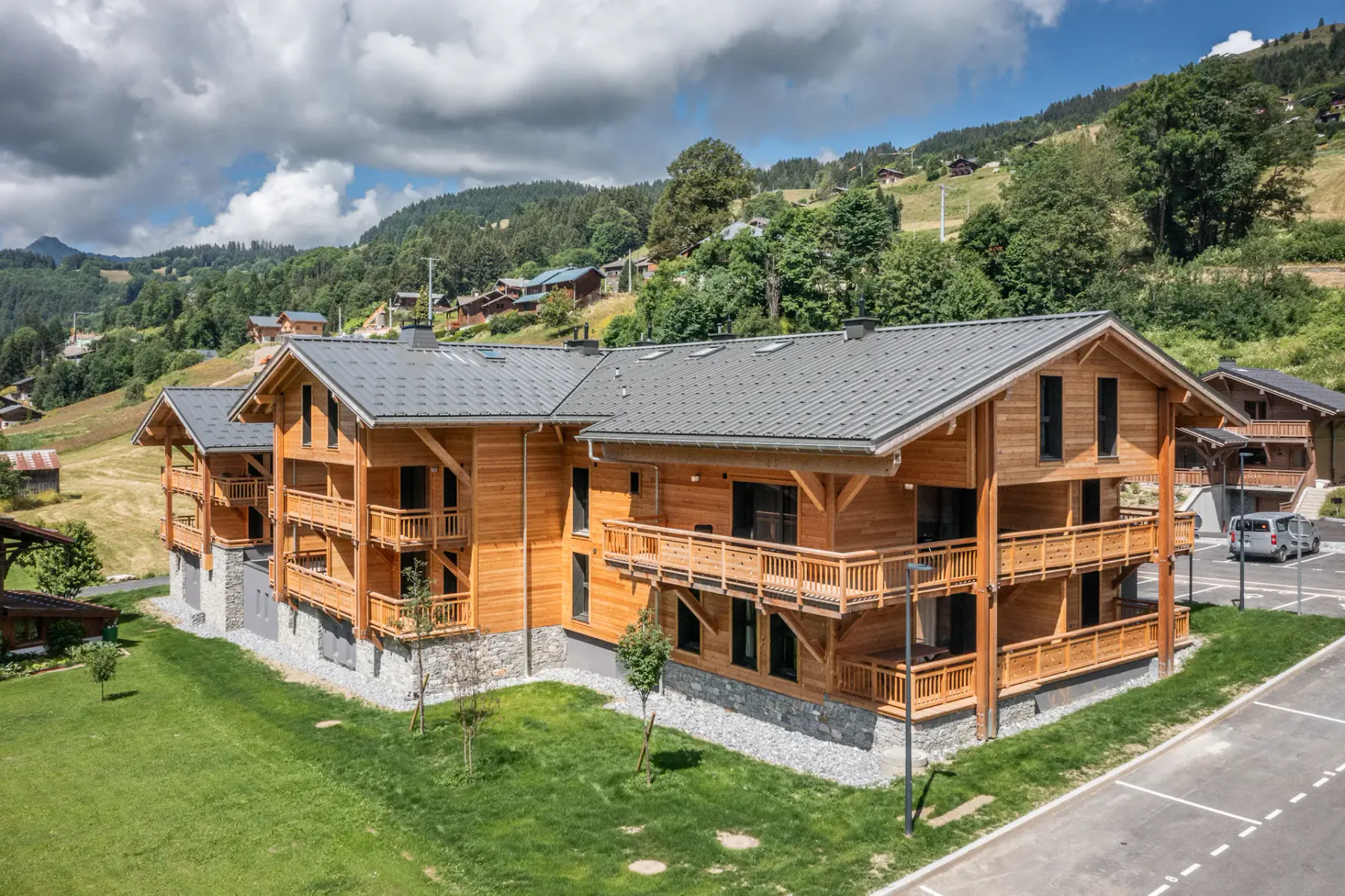 Shared amenity: A wooden building with balconies stands beside a grassy area in a mountain village.