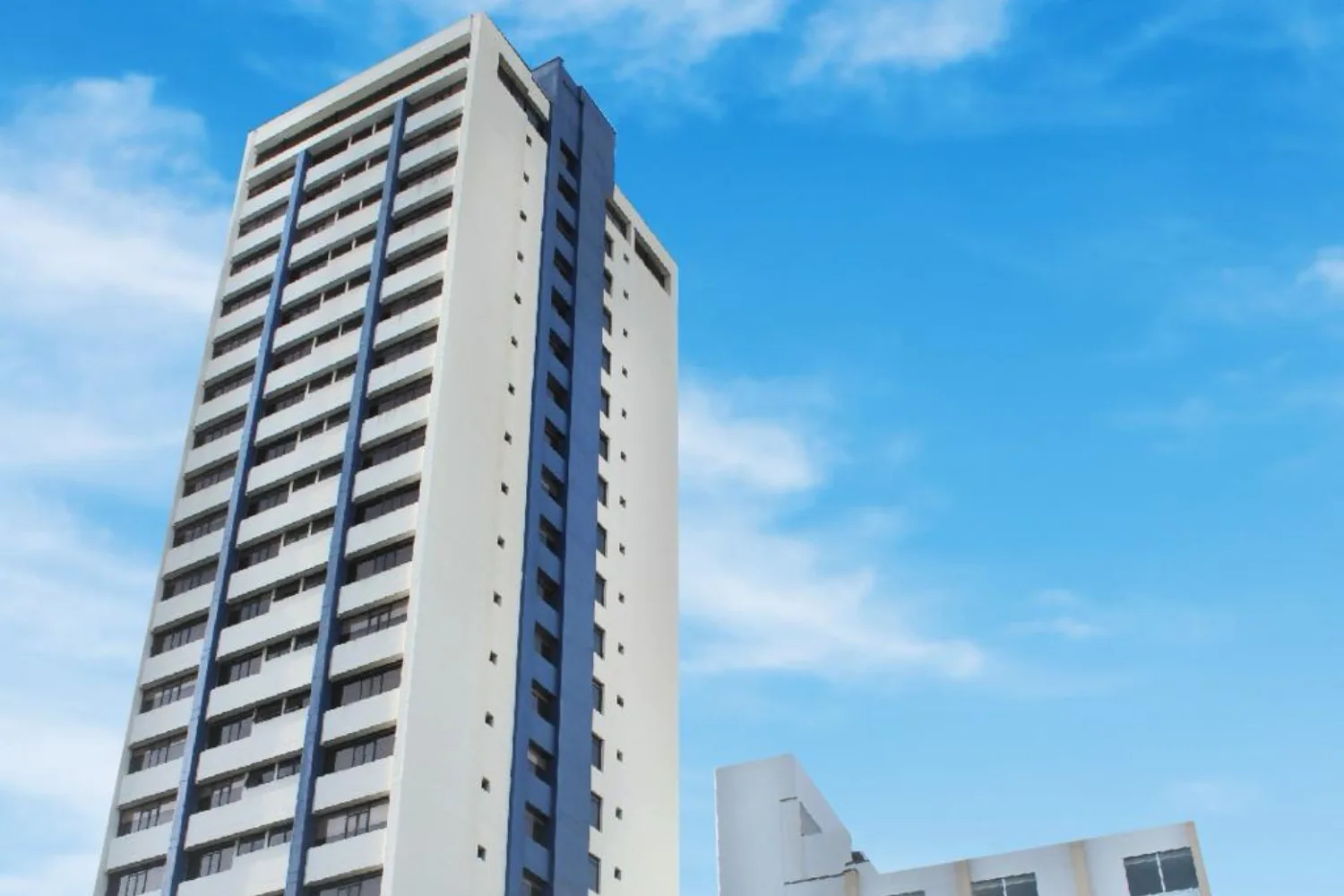 Espacio representativo del hotel: Un edificio moderno y alto se alza contra un cielo azul.
