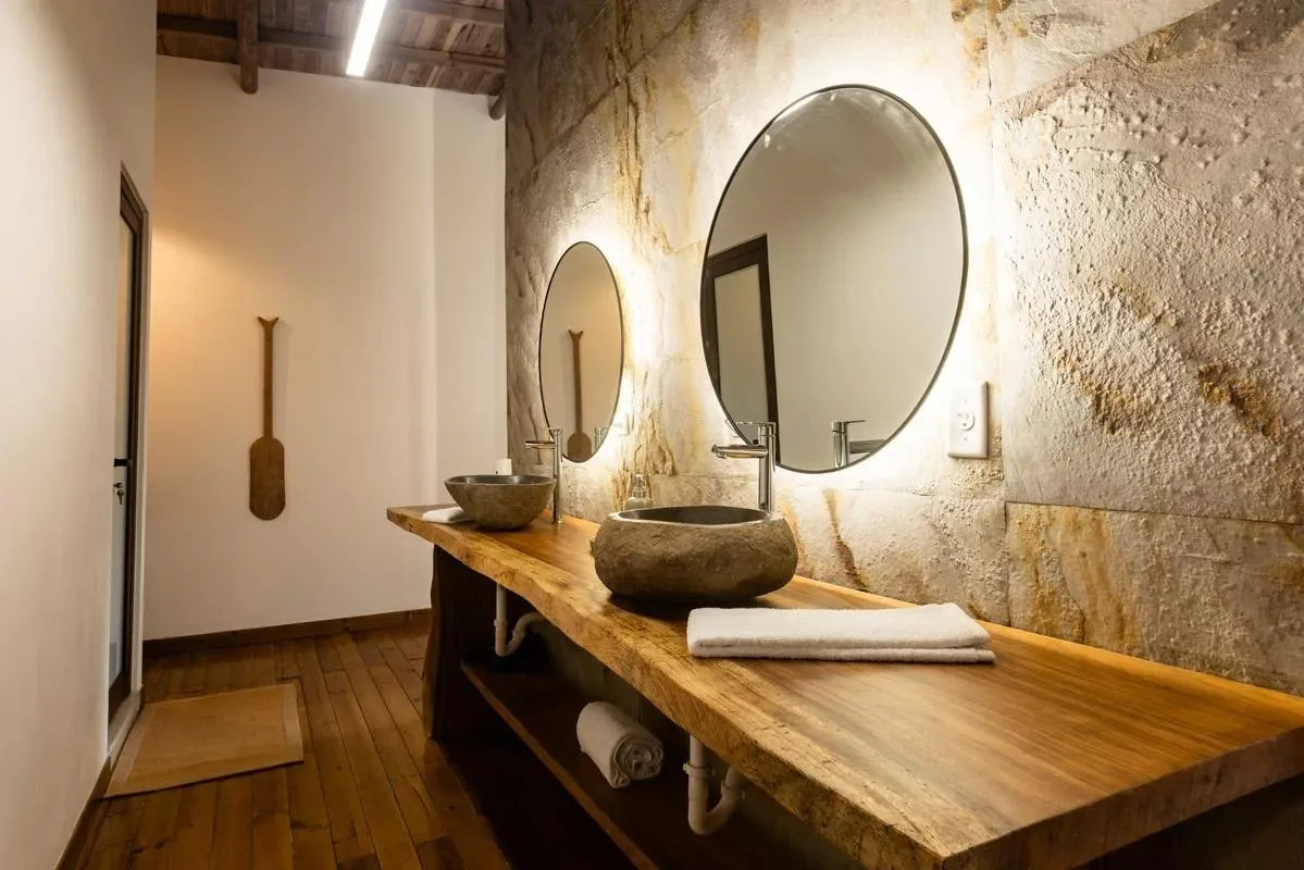 A rustic bathroom vanity with stone basins and round mirrors.