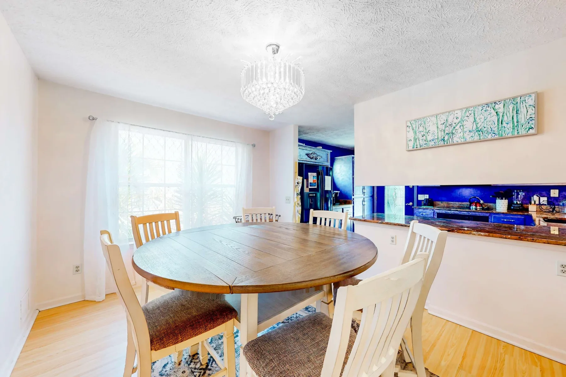 A dining area with a wooden table and chairs beside a bright window.