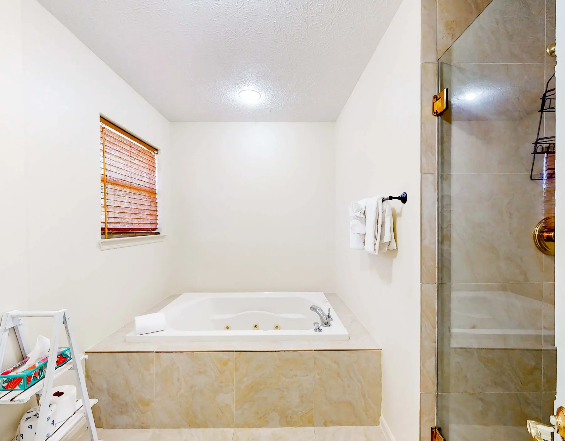 A bright bathroom with a built-in tub and a glass shower.