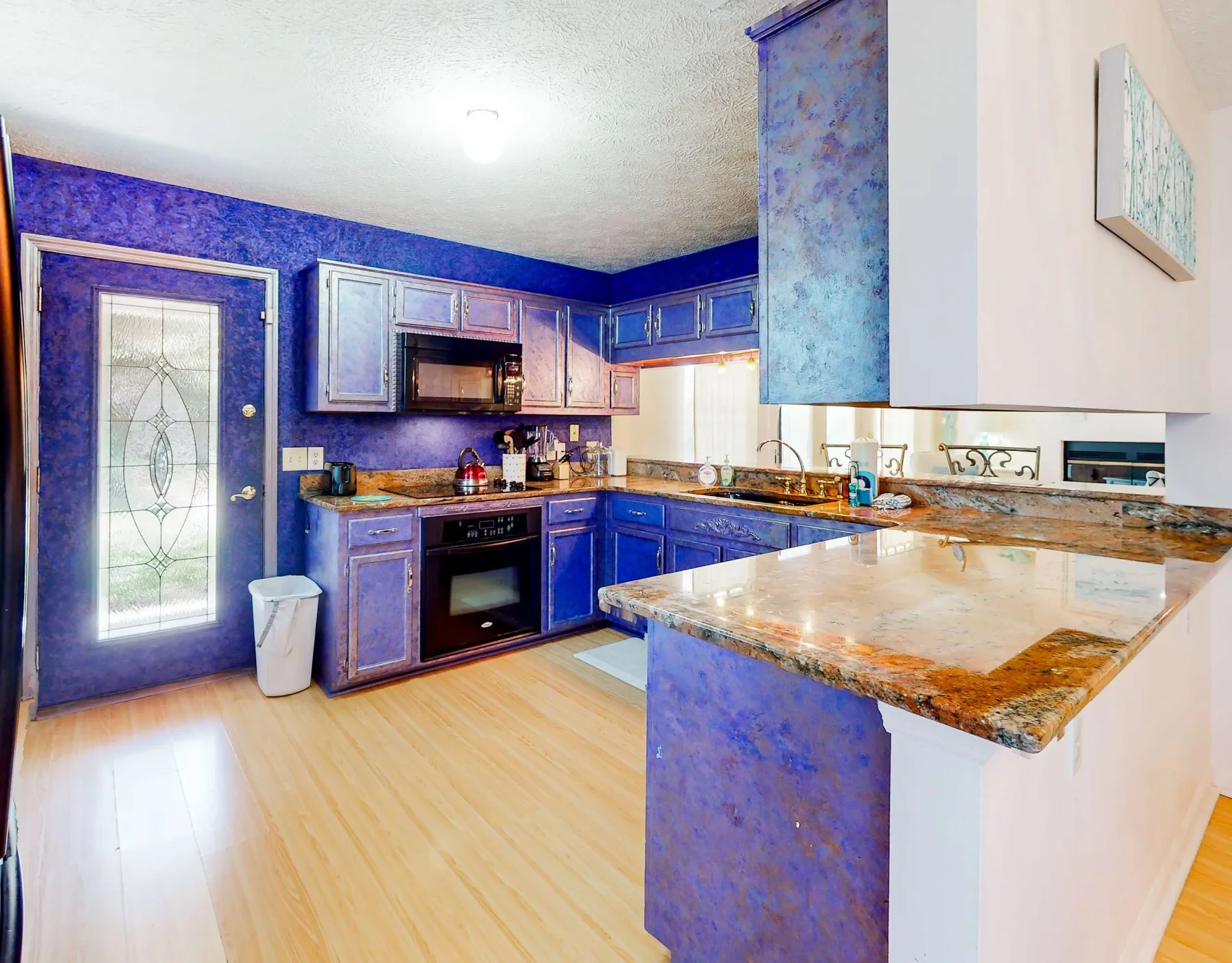 A kitchen with blue cabinets, appliances, and a large counter.