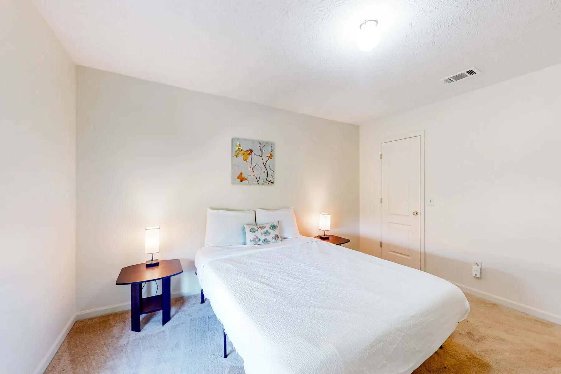 A bright bedroom with a neatly made bed and matching bedside tables.
