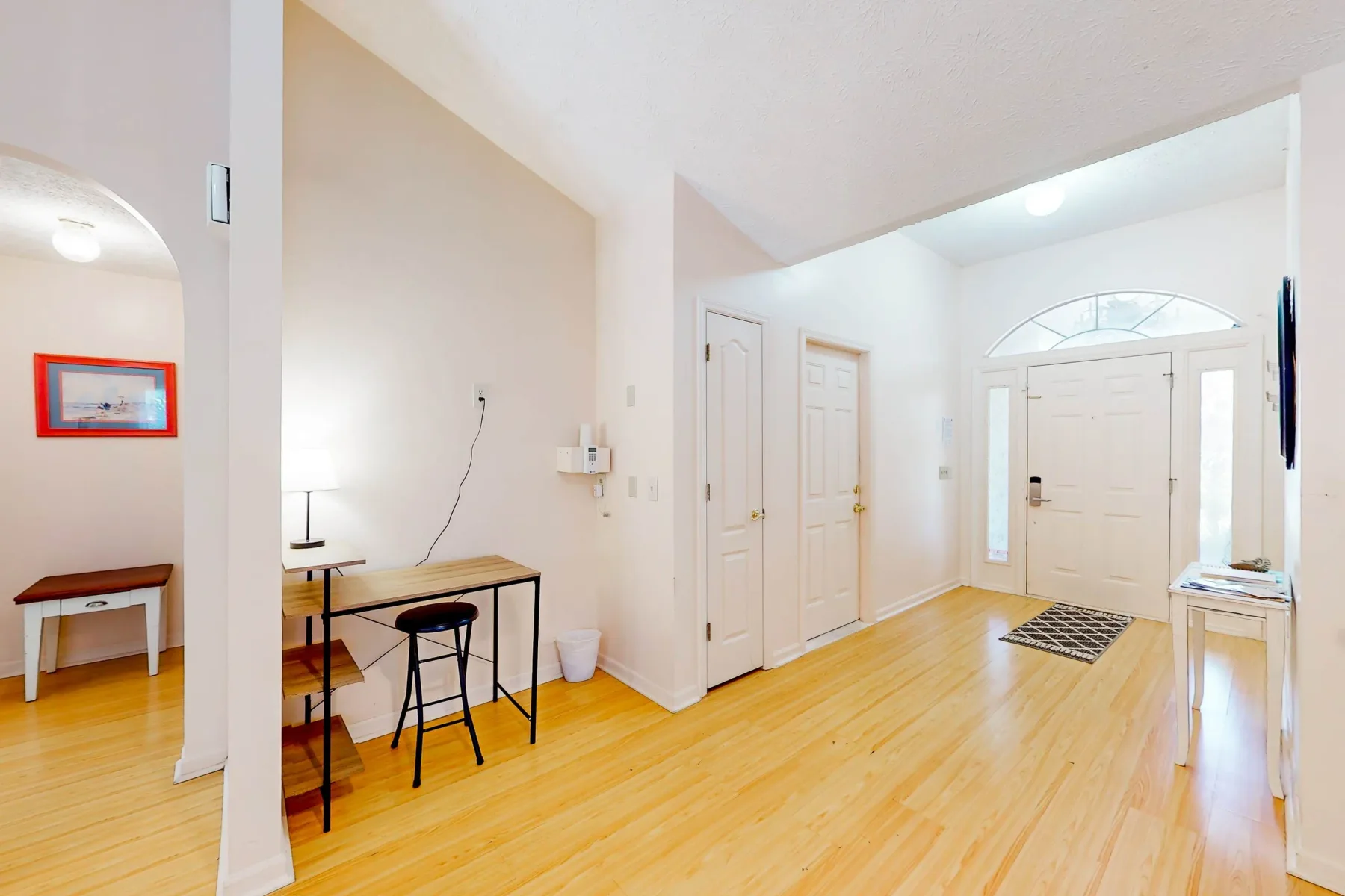 A bright entryway with a front door and a small desk against the wall.