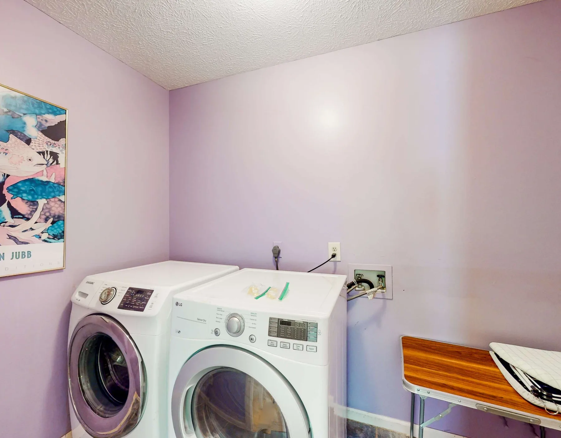 A laundry area with a washer and dryer against pale purple walls.