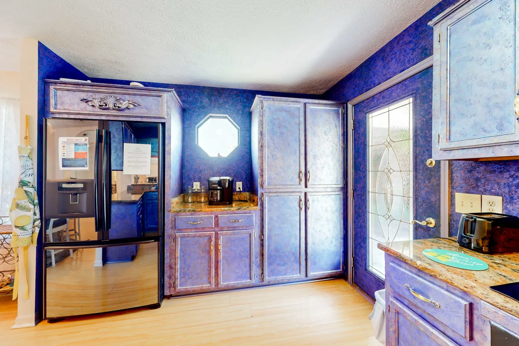 A kitchen with blue cabinets, a refrigerator, and a countertop.