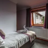 Espacio representativo del hotel: Un dormitorio con una cama junto a una ventana y un radiador.