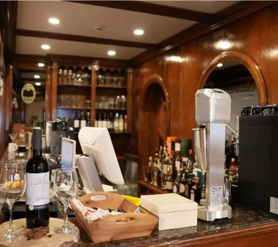 Espacio representativo del hotel: Una barra exhibe botellas, cristalería y equipo para preparar bebidas.