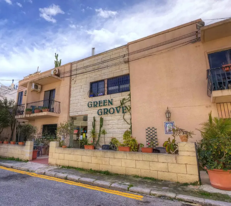 Espacio representativo del hotel: Exterior de hotel con fachada de piedra, balcones y plantas junto a la acera.