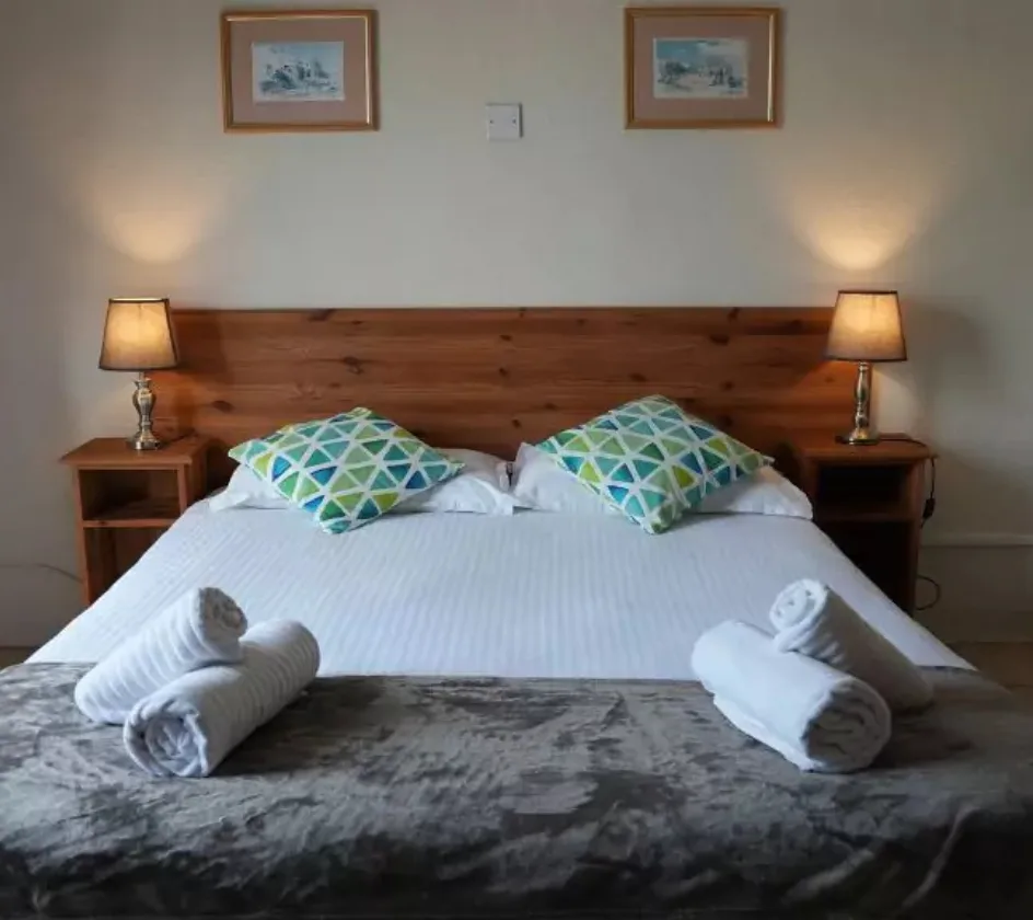 Espacio representativo del hotel: Un dormitorio con una cama bien hecha y lámparas a ambos lados.