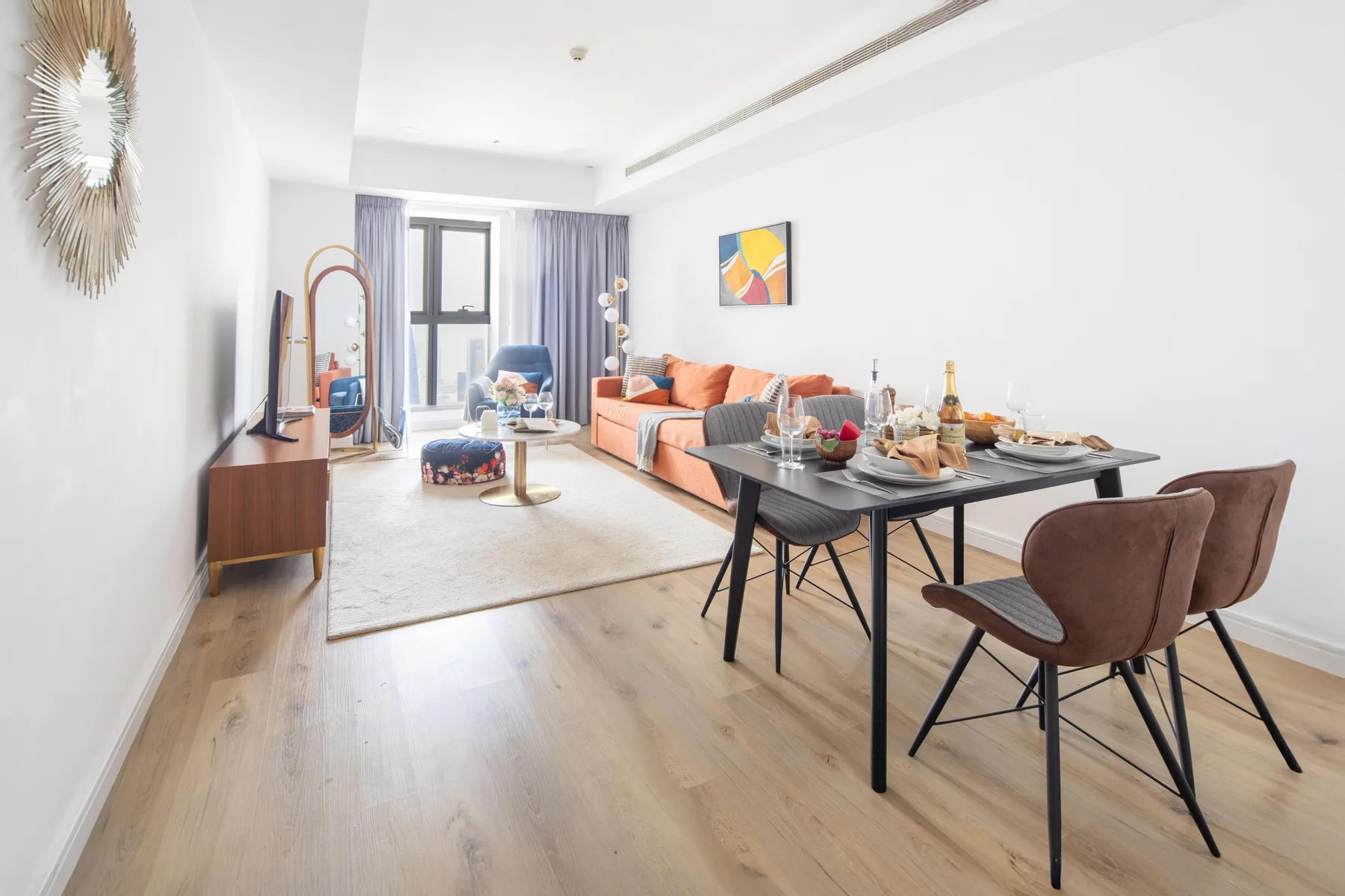 A bright living and dining area with a sofa and a set dining table.