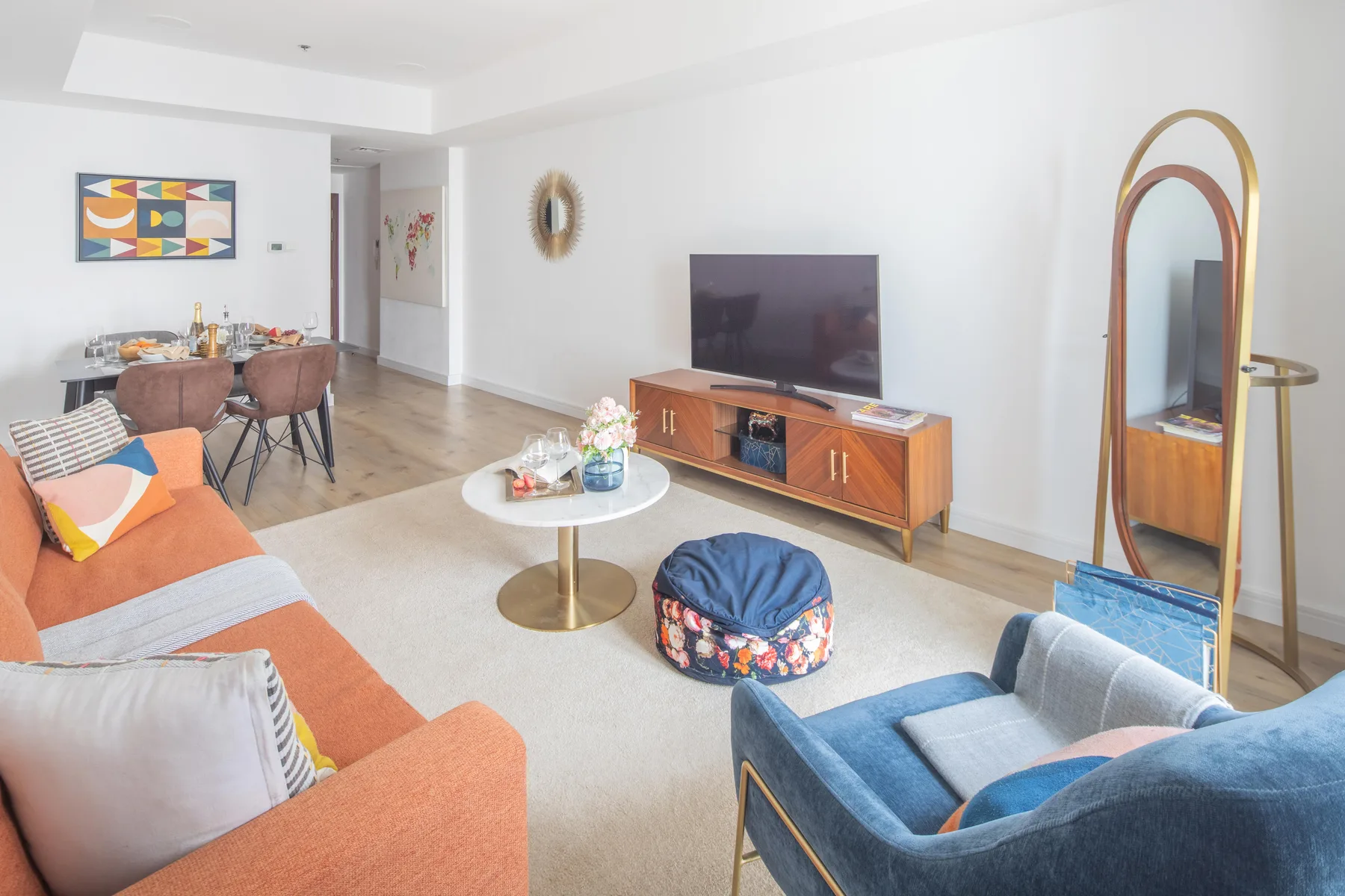 A bright living room with seating, a television, and a dining area.