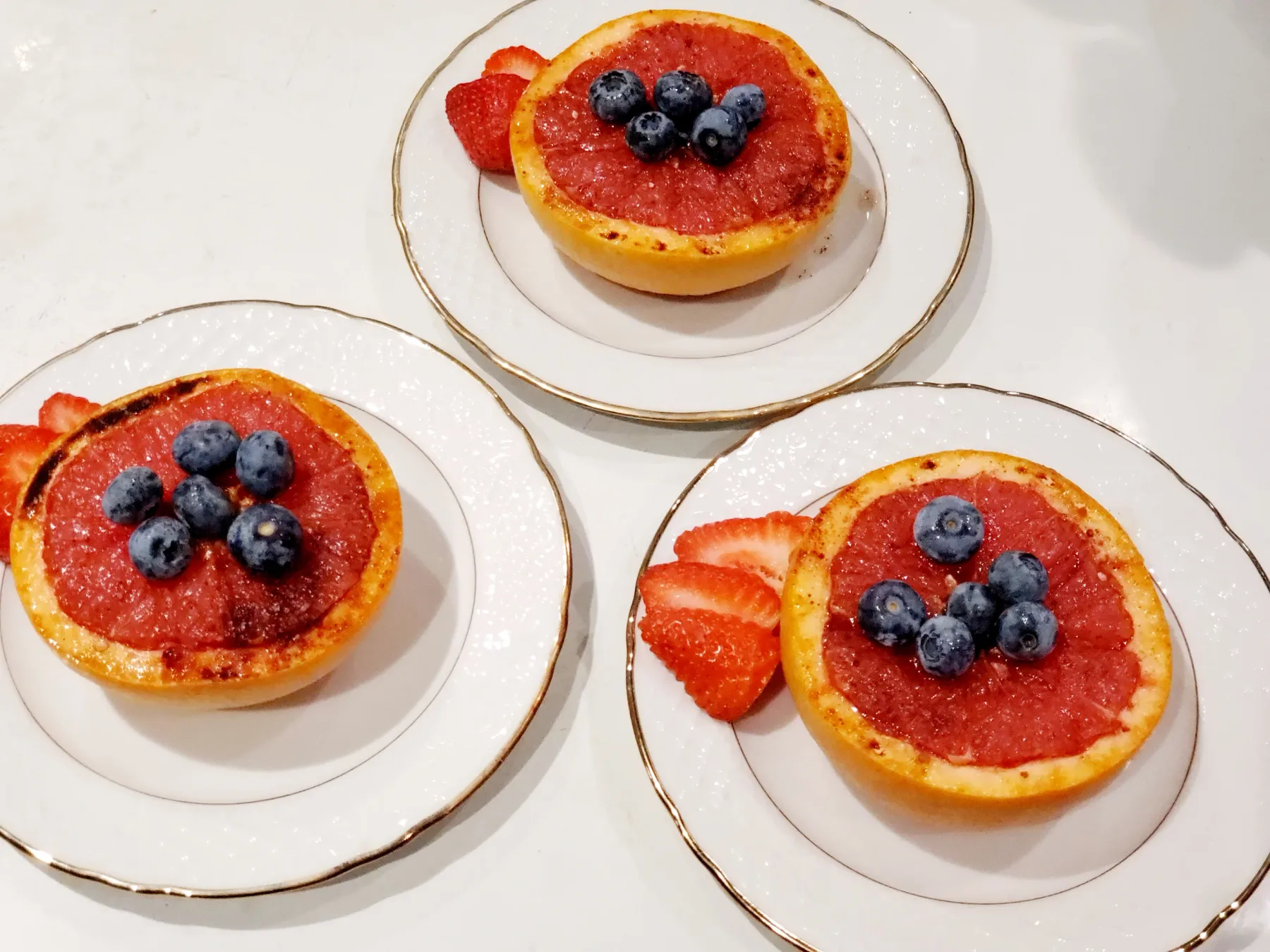 Representative hotel space: Three plates hold grapefruit halves topped with blueberries and strawberry slices.