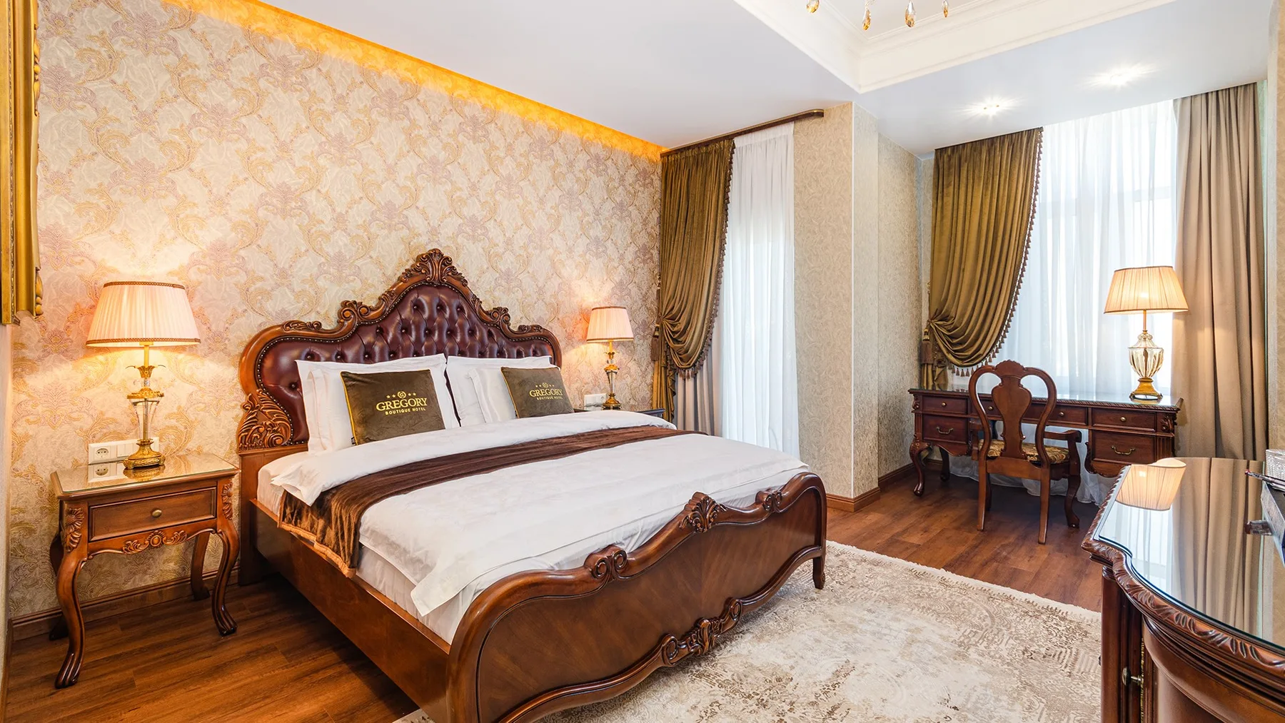 Representative hotel space: A bedroom with an ornate wooden bed, bedside tables, and a desk by the windows.