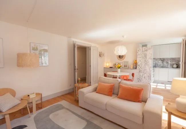 A bright living room with a sofa facing a small dining area.