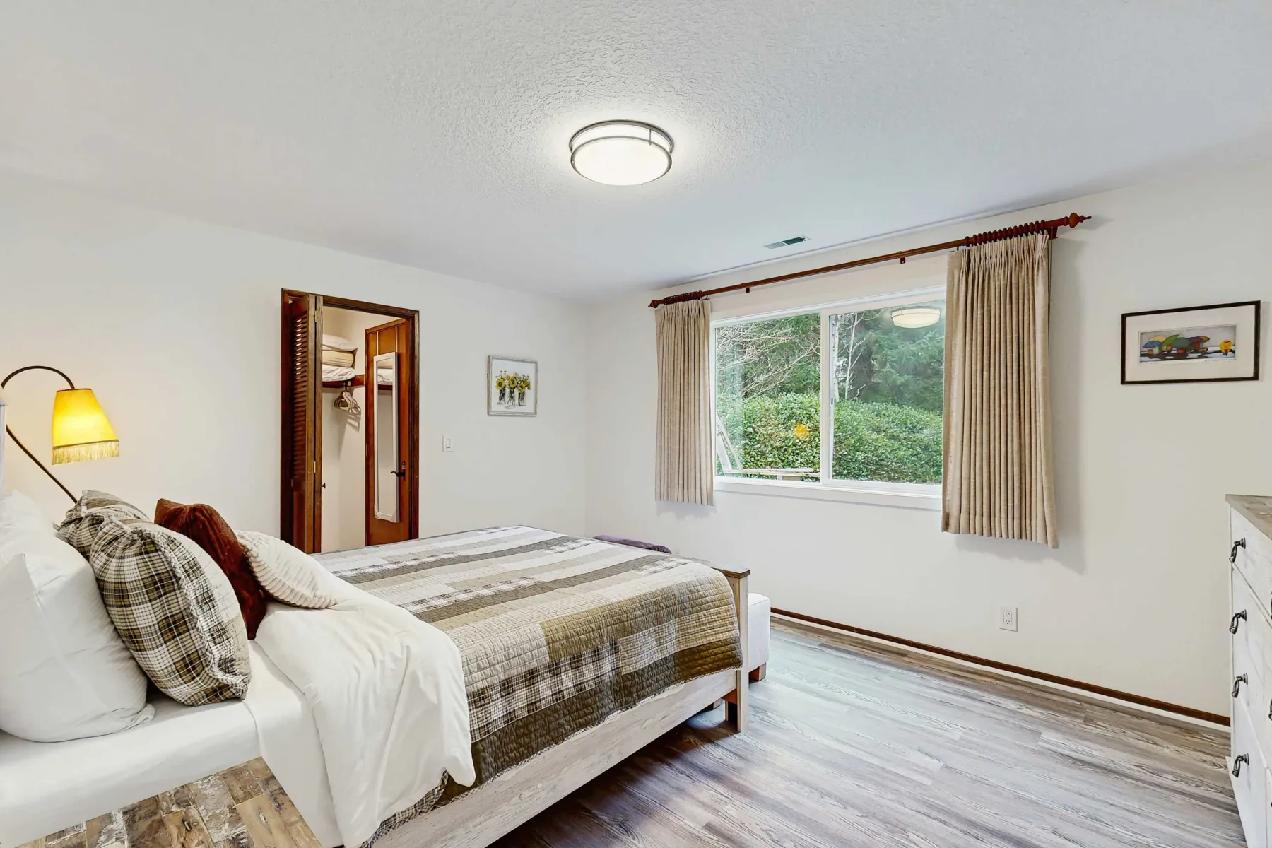 Un dormitorio con una cama junto a una ventana grande con cortinas.