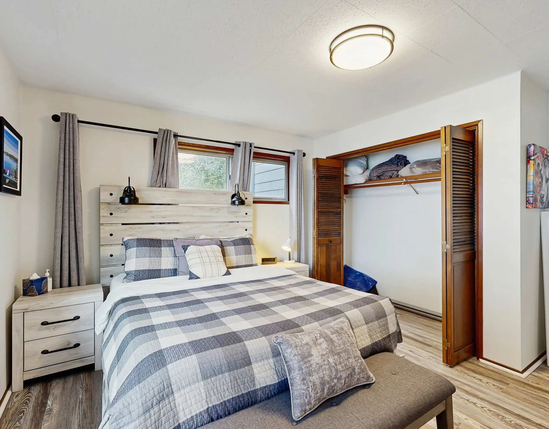 Dormitorio con una cama, ropa de cama a cuadros y un armario abierto.