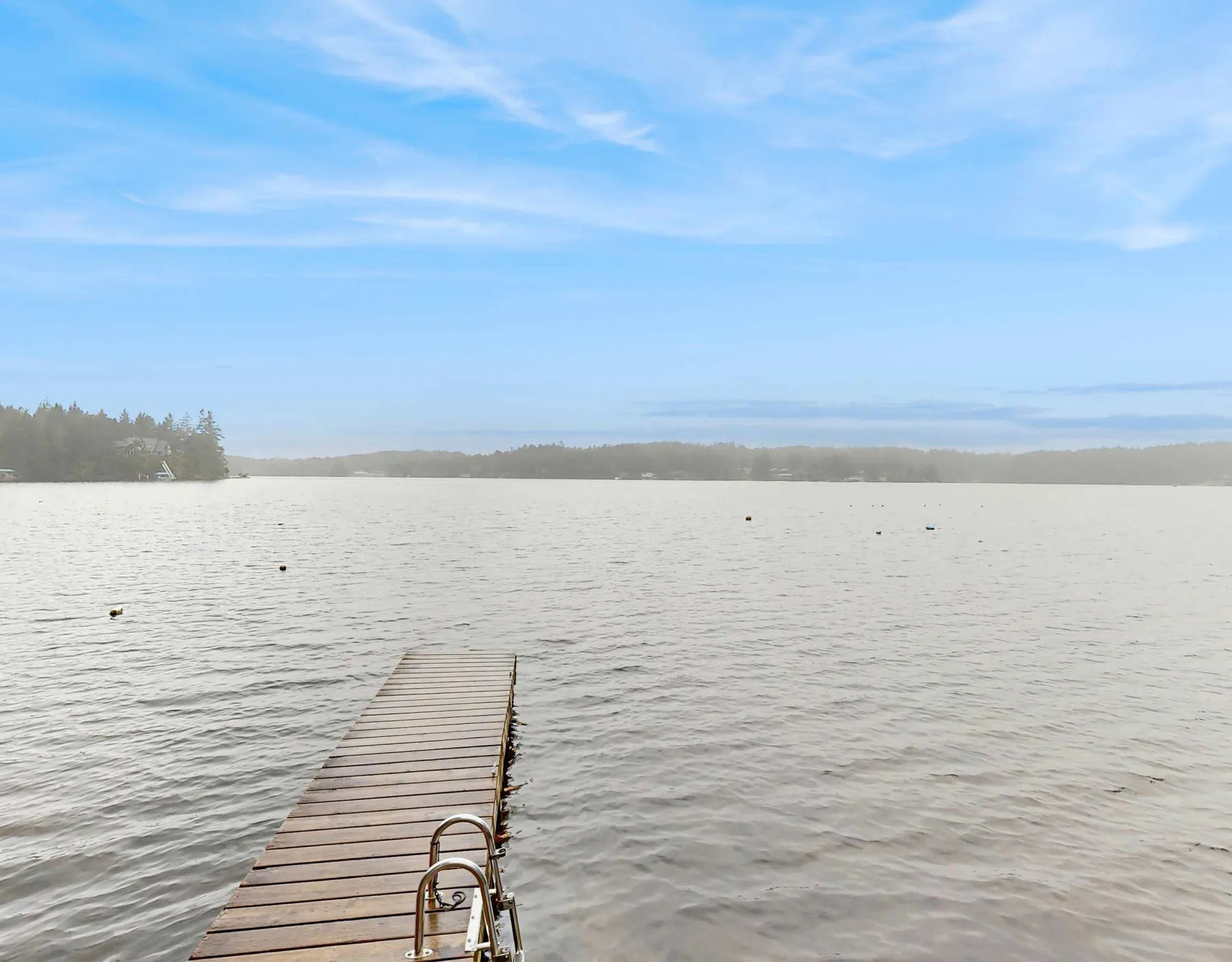 Un muelle de madera se adentra en un lago bajo un cielo azul despejado.