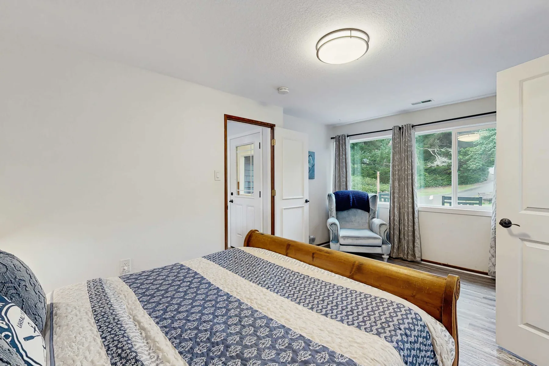 Un dormitorio con una cama y una zona de estar junto a grandes ventanas.